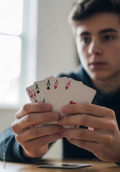 Fototapeta Young man holding four aces playing cards in his hands at the table