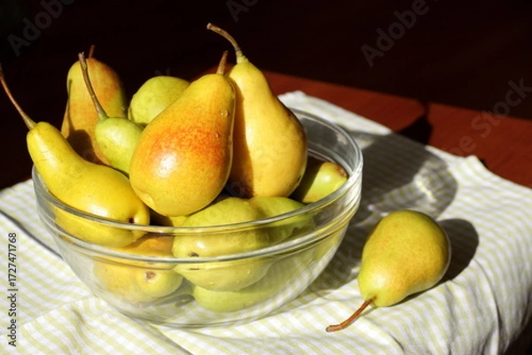 Fototapeta Juicy ripe sweet pears in a glass transparent bowl on a table with a checkered green napkin