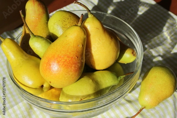 Fototapeta Juicy ripe sweet pears in a glass transparent bowl on a table with a checkered green napkin