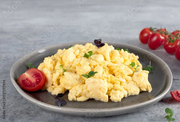 Fototapeta Scrambled eggs with green onions and tomato on a gray plate on gray background. Healthy breakfast. 