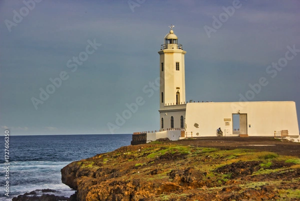 Fototapeta Landscape with white lighthouse under the sunlight on the African coast of the ocean.