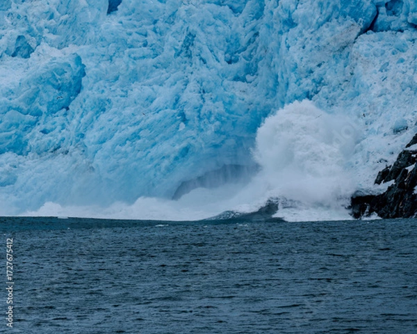 Fototapeta Calving action at Aialak Glacier causes a massive sea swell crashing into rocks
