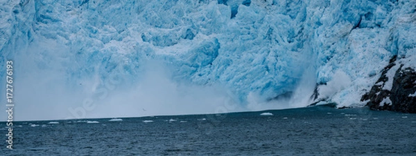 Fototapeta Calving action at Aialak Glacier causes a massive sea swell crashing into rocks
