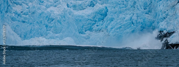 Fototapeta Calving action at Aialak Glacier causes a massive sea swell crashing into rocks