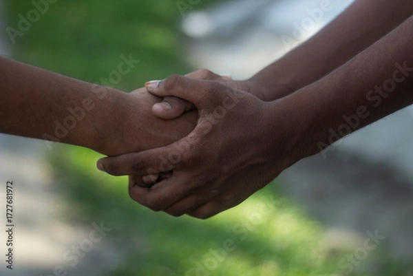 Fototapeta Two hands clasping in a gesture of support and unity outdoors