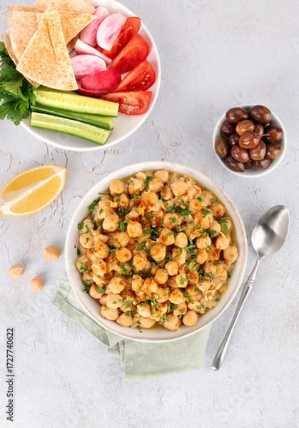 Fototapeta Levantine balila or msabah made with warm chickpeas, olive oil and spices and fresh vegetables on white background