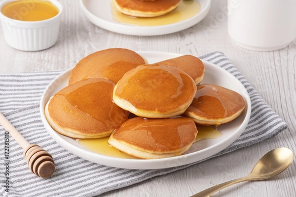 Fototapeta Delicious fluffy pancakes with syrup served on a white plate for breakfast