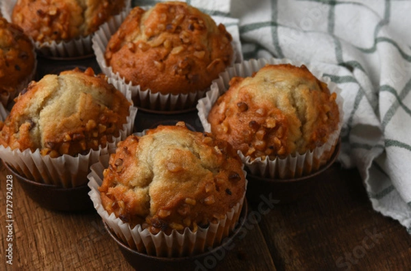Obraz Muffin pan with six fresh baked Banana ut Muffins on a rustic wood kitchen table.