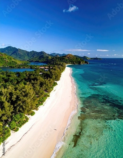 Obraz Aerial view of a pristine, secluded beach with white sand, turquoise water, lush greenery, and distant mountains under a vibrant blue sky