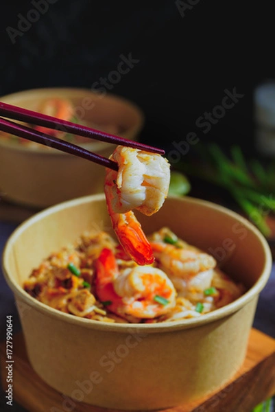 Fototapeta Pad Thai stir-fried with shrimp, eggs, peanuts and lime, served in paper.