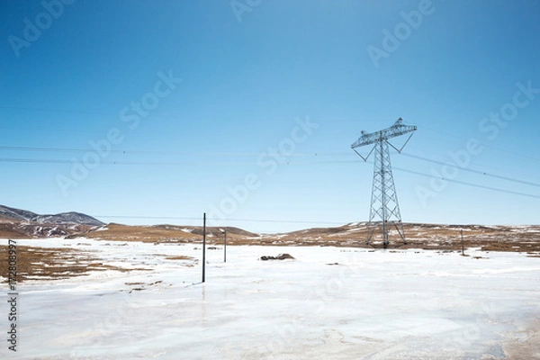 Fototapeta power pylon in wild field with snow
