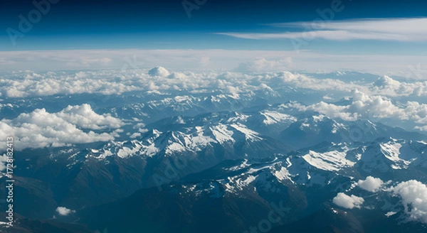 Fototapeta Aerial View of Snow-Capped Mountain Range Under Blue Sky with Clouds