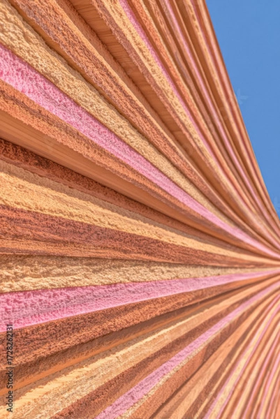 Fototapeta Colorful architectural design features vibrant ridged patterns against a clear blue sky in a modern setting