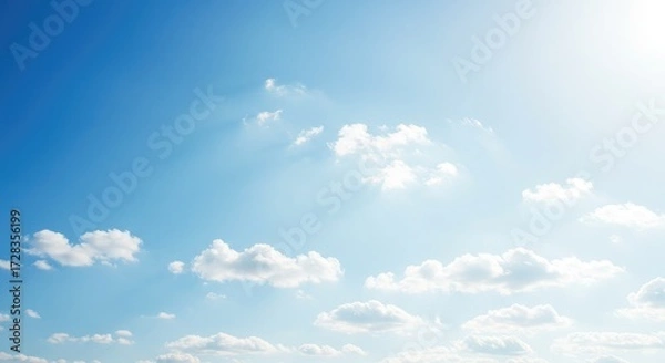 Fototapeta Vibrant blue sky filled with fluffy white clouds and gentle sunbeams creating a serene and uplifting atmosphere, perfect for aspirational and peaceful projects.