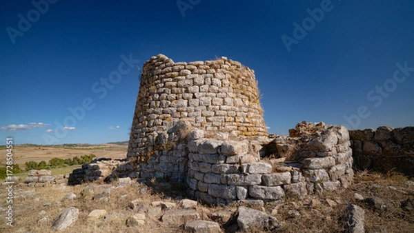 Fototapeta Nuraghe Piscu megalithic stone tower ruins in Suelli, Sardinia, under clear blue sky