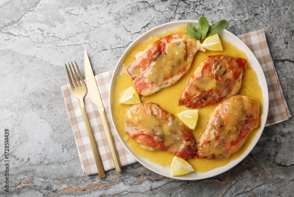 Obraz Chicken Saltimbocca is an Italian-inspired dish made with thin chicken cutlets wrapped in prosciutto and sage and lemony white wine sauce closeup on the plate on the table. Horizontal top view