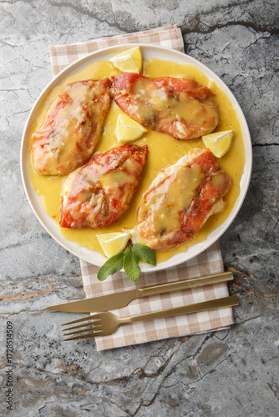 Obraz Tasty Chicken Saltimbocca has been wrapped with prosciutto and sage in a white wine butter sauce closeup on the plate on the table. Vertical top view from above