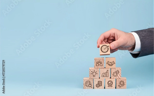 Obraz Building Business Goals from Strategic Foundations, Hand places target icon atop pyramid of business concept blocks