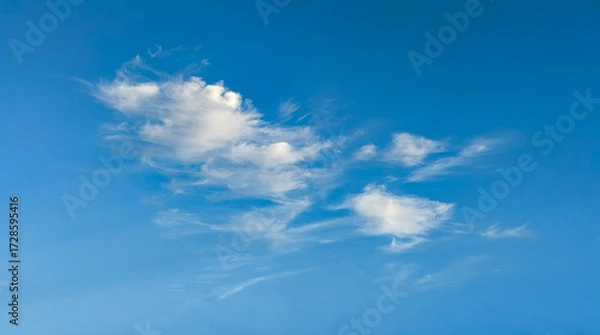 Fototapeta Blue sky with cloud. Mixed cumulus and cirrus clouds are scattered by the wind across the vast sky on light background.