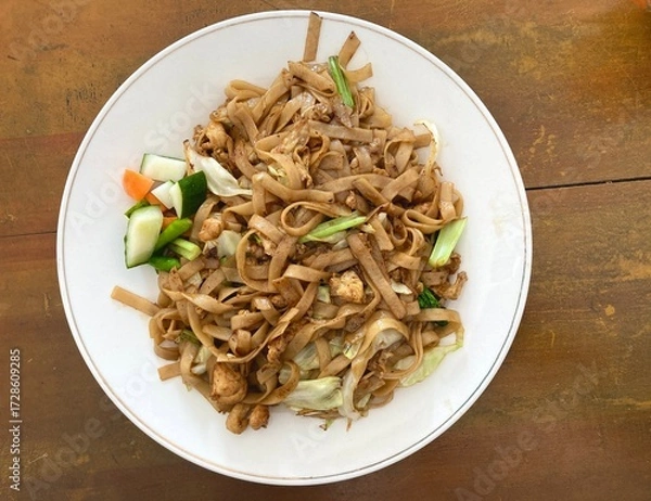 Fototapeta Top view of a plate of stir-fried flat noodles served with vegetables and chicken