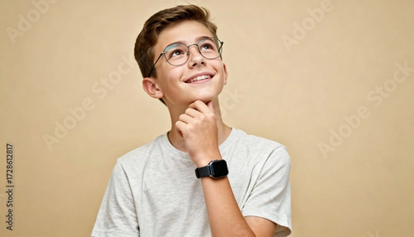Fototapeta Pensive happy student thinking, looking up with a smile. Thoughtful young teenager contemplating an idea. Concept of dreaming, inspiration, and problem-solving. Smart kid.