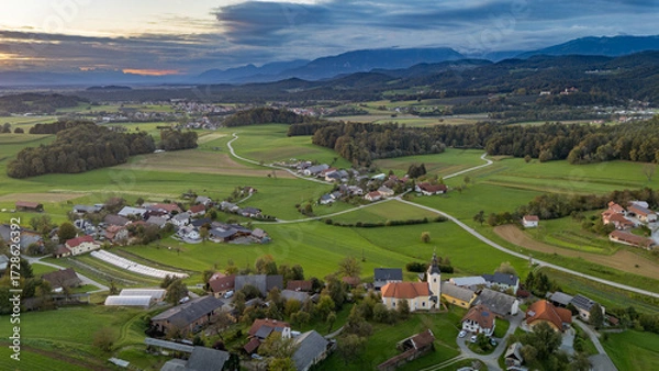 Fototapeta defaultAerial view of Spodnje Koseze near Lukovica, Slovenia, showing a scenic rural landscape with green fields, red-roofed houses, and forested hills under a dramatic sky