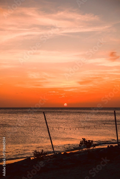 Obraz Floating in the waves at sunset, sun just above horizon, going down, orange sky, tranquil sea. Peaceful moment, vacations, summer mood. Dominican Republic. Horizontal video.