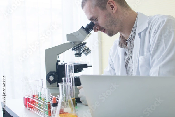 Fototapeta Medical or scientific researcher or man doctor looking at a test tube of clear solution in a laboratory