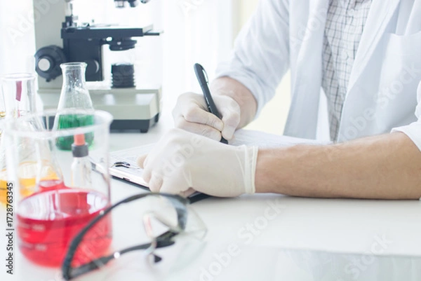 Fototapeta Medical or scientific researcher or man doctor looking at a test tube of clear solution in a laboratory
