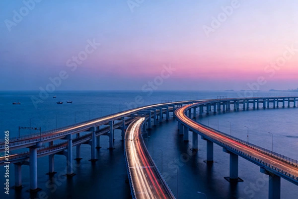 Fototapeta Long exposure view of a curved bridge over the sea at twilight with light trails from vehicles