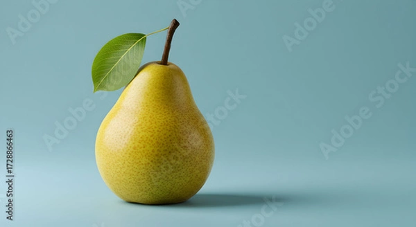 Fototapeta A vibrant yellow pear with a stem and leaf isolated against a pastel blue backdrop
