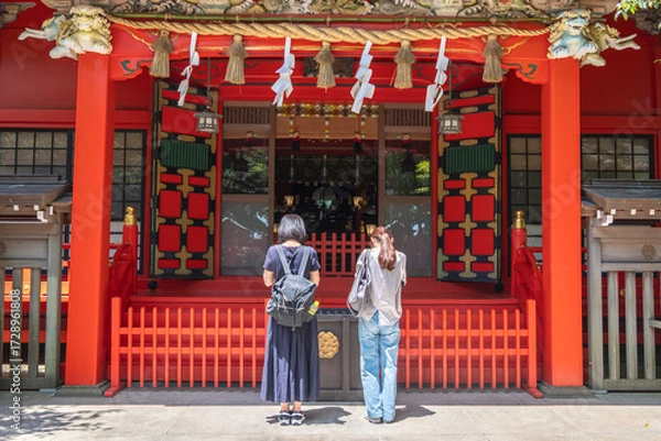 Fototapeta Two women praying at traditional Japanese shrine entrance outdoors at Enoshima, Kamakura, Kanagawa, Japan