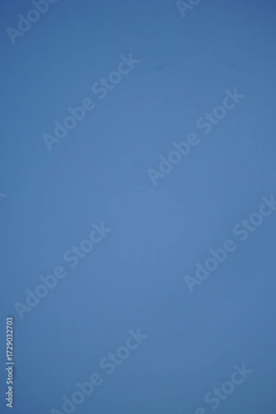 Fototapeta A clear, vibrant blue sky with no clouds, providing a clean and serene natural background. Perfect for themes of freedom, space, or a bright day.

