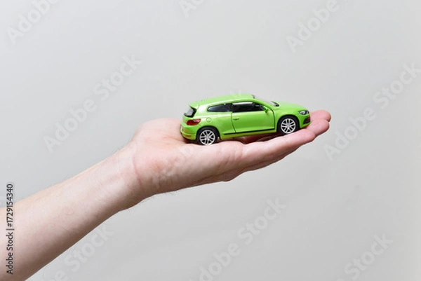 Fototapeta Man's hand holds a small car model