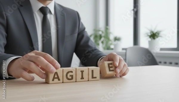 Fototapeta Agile Strategy: A focused businessperson meticulously arranges wooden blocks that spell 'AGILE', a visual representation of adaptable business planning.
