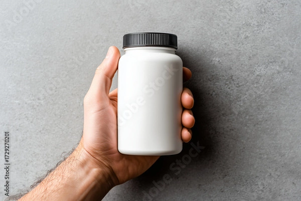 Fototapeta hand holding supplement bottle with blank label against simple backdrop