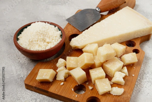 Obraz Freshly sliced and grated cheese, parmesan cheese, on a wooden chopping board, rustic style, no people