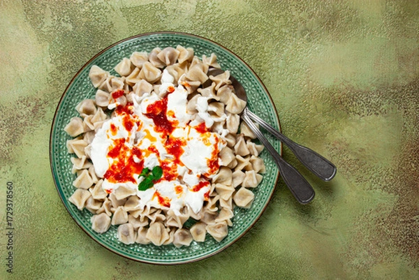 Obraz Traditional Turkish dumplings served with yogurt and spicy sauce on a green decorative plate