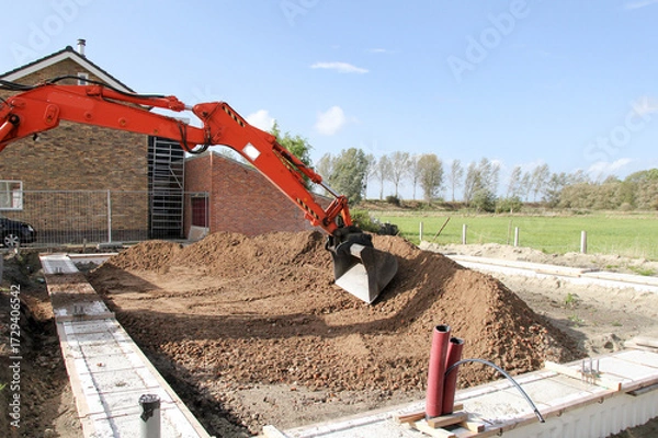 Fototapeta the arm and bucket of a mobile excavator is adjusting ground at a construction site in the countryside 