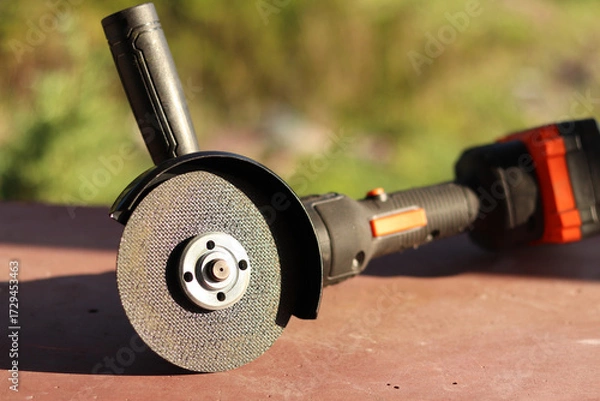 Fototapeta Angle grinder with battery. Power tool close-up. Angle grinder on the veranda. Repair and construction tool. Angle grinder with handle