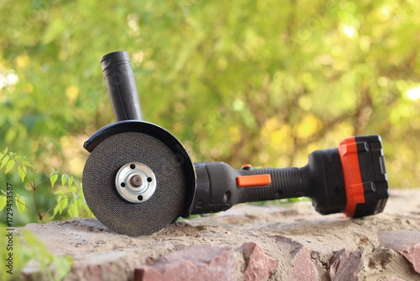 Fototapeta Angle grinder with battery. Power tool close-up. Angle grinder on the veranda. Repair and construction tool. Angle grinder with handle