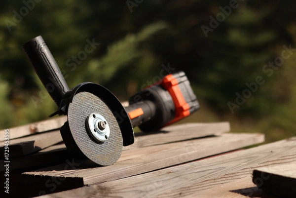 Fototapeta Angle grinder with battery. Power tool close-up. Angle grinder on the veranda. Repair and construction tool. Angle grinder with handle