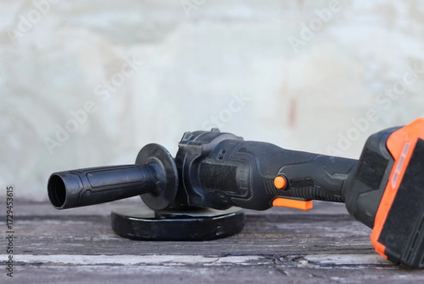 Fototapeta Angle grinder with battery. Power tool close-up. Angle grinder on the veranda. Repair and construction tool. Angle grinder with handle