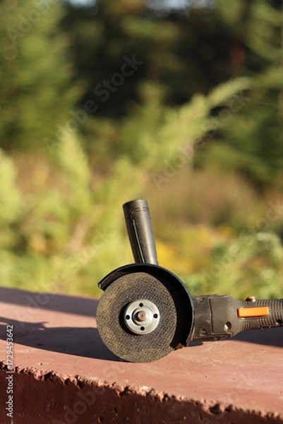 Fototapeta Angle grinder with battery. Power tool close-up. Angle grinder on the veranda. Repair and construction tool. Angle grinder with handle
