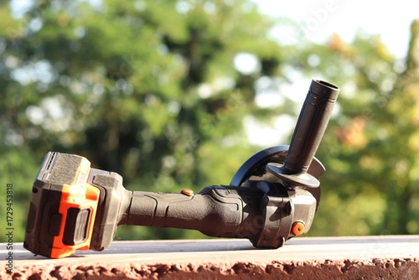 Fototapeta Angle grinder with battery. Power tool close-up. Angle grinder on the veranda. Repair and construction tool. Angle grinder with handle