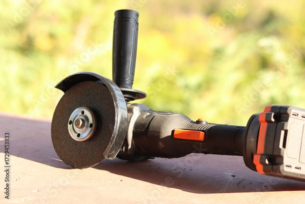 Fototapeta Angle grinder with battery. Power tool close-up. Angle grinder on the veranda. Repair and construction tool. Angle grinder with handle