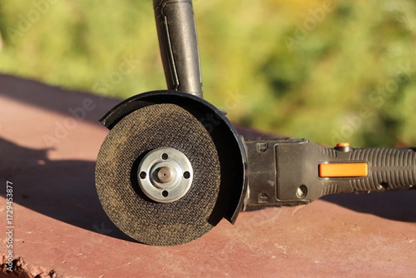 Fototapeta Angle grinder with battery. Power tool close-up. Angle grinder on the veranda. Repair and construction tool. Angle grinder with handle