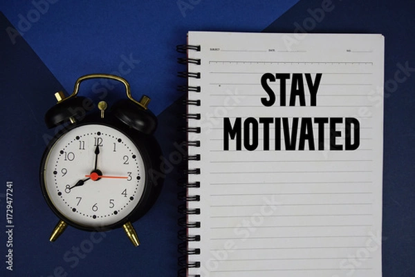 Obraz Stay Motivated text written on notepad with alarm clock on blue background