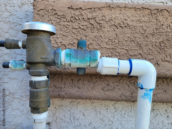 Fototapeta Side View of misaligned and broken junction of bronze alloy and plastic water pipe branching to drop irrigation system, close up