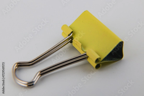 Obraz Bright yellow binder clip on a white background for office organization